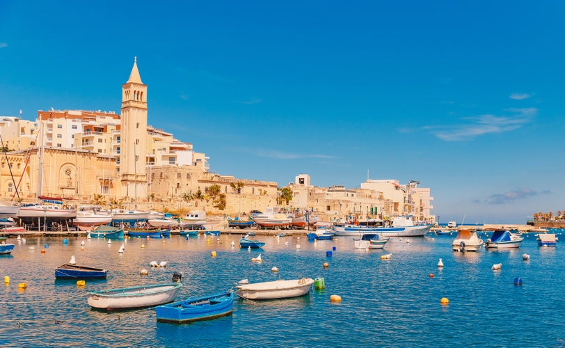 Photo of city Marsaskala  summer harbour Fishing boats in water of Mediterranean blue sea , Malta.