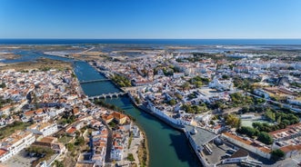 Photo of aerial cityscape of beautiful Tavira with roman bridge over Gilao river in the evening, Algarve, Portugal.