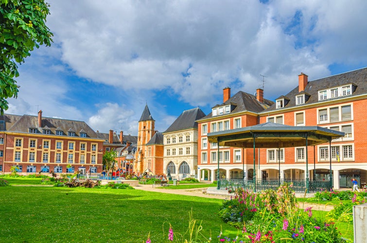 Bandstand band shell music pavilion stage in Square Jules Bocquet, lawn with green grass and flowers and Maison du Sagittaire Sagittarius house in Amiens city centre, Hauts-de-France Region, France