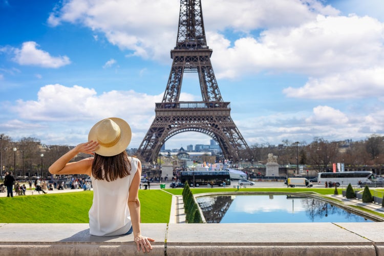 A tourist woman enjoys the beautiful view of the Eiffel Tower in Paris, France.jpg