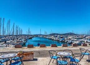 Photo of aerial view of Alghero on a beautiful day with harbor and open sea, Italy.