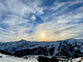 Photo of Dornbirn at sunset with a view of the meadows, forests and snowy mountains in background, Austria.