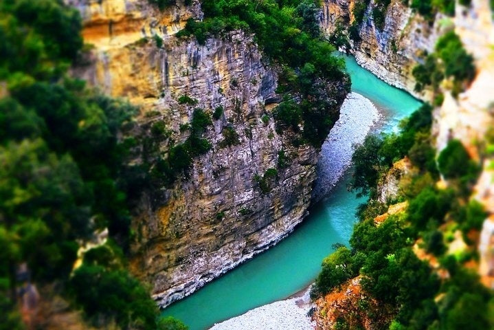 A narrow turquoise river flows between high rocky cliffs covered with green trees and bushes in Osumi Canyon..jpg