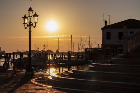 First rays of sunrise illuminate steps of bridge Ponte di Vigo stretching across the enchanting Canal Vena in Chioggia, Venetian Lagoon, Veneto, Italy. Exquisite display of Venetian architecture