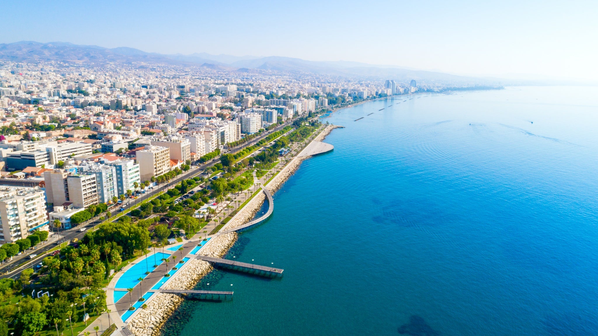 Aerial view of Molos Promenade park on coast of Limassol city centre,Cyprus. Bird-s eye view of the jetty, beachfront walk path, palm trees, Mediterranean sea, piers, urban skyline and port.jpg