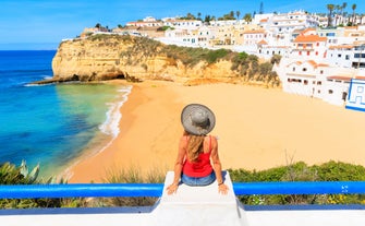 Photo of beautiful aerial view of the sandy beach surrounded by typical white houses in a sunny spring day, Carvoeiro, Lagoa, Algarve, Portugal.