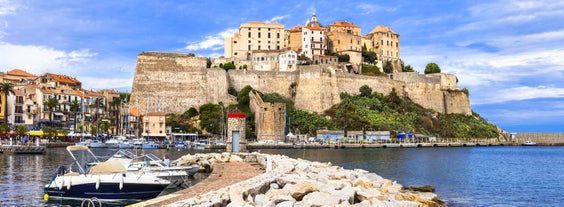 Photo of aerial view from the walls of the citadel of Calvi on the old town with historic buildings and bay with yachts and boats, Corsica, France.