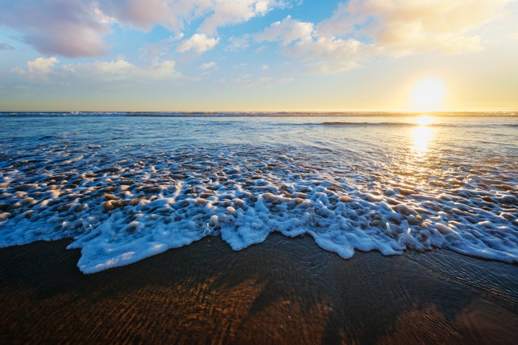 Photo of Atlantic ocean sunset with surging waves at Fonte da Telha beach, Costa da Caparica, Portugal.