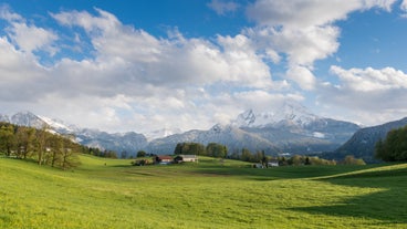 photo of Elevated, scenic view of the town of Bischofswiesen, Bavaria, Germany. The Watzmann Mountain, part of the Bavarian Alps rises into a majestic skyline. A green, spring landscape set in the valley.