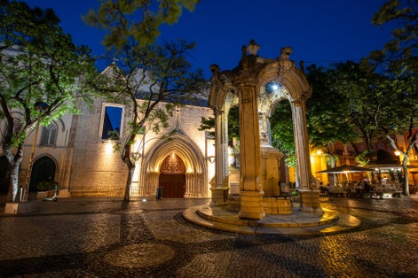 Photo of An evening view of the baroque fountain and exterior of Carmo Convent in Largo do Como in the beautiful city of Lisbon, Portugal.