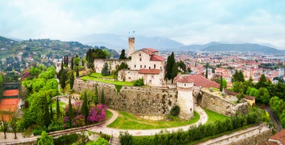 Photo of Old harbour Porto Vecchio with motor boats on turquoise water, green trees and traditional buildings in historical centre of Desenzano del Garda town, Northern Italy.