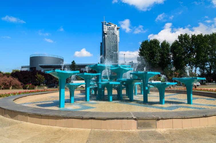 Photo of Water fountain in public park with view of tall tower building, Gdynia city waterfront, Poland