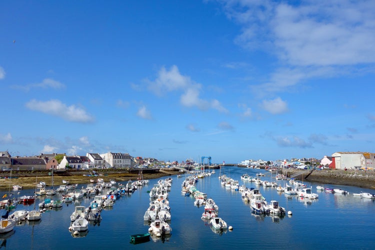 Fishing boats and pleasure boats in the port of Guilvinec, France, under the blue sky.