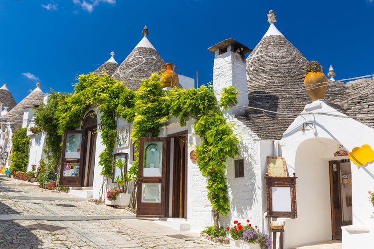 Beautiful town of Alberobello with trulli houses among green plants and flowers, main touristic district, Apulia region, Southern Italy.