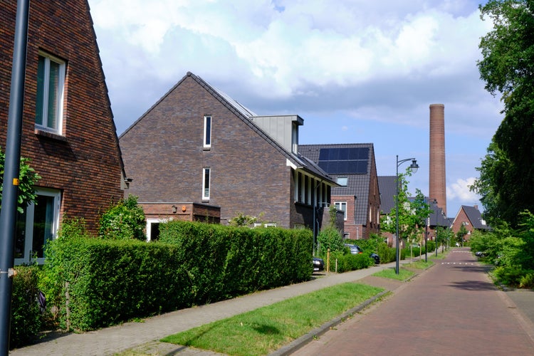 photo of street , new houses, old Enka factory site old chimney. New residential area after soil remediation in Ede, the Netherlands.