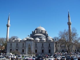 Touristic sightseeing ships in Golden Horn bay of Istanbul and mosque with Sultanahmet district against blue sky and clouds. Istanbul, Turkey during sunny summer day.