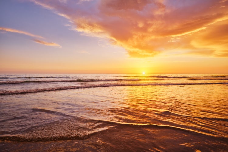 Photo of Atlantic ocean sunset with surging waves at Fonte da Telha beach, Costa da Caparica, Portugal.