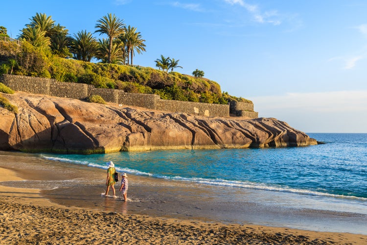 photo of a mother and son walking on tropical sandy El Duque beach in Costa Adeje, Tenerife, Canary Islands, Spain.