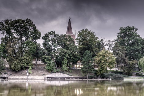 The Piast Tower behind trees in Opole, Poland under the stormy sky