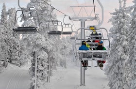 Photo of stunning sunset view over wooden huts and snow covered trees in Kuusamo, Finnish Lapland.