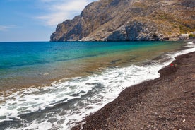 Photo of aerial view of black Perissa beach with beautiful turquoise water, sea waves and straw umbrellas, Greece.