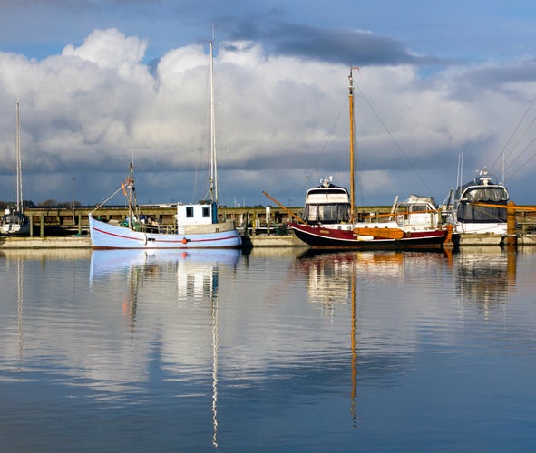 photo of view of Colorful fishing boats with reflections in the calm waters of the fishing harbor of Lemvig, Denmark.