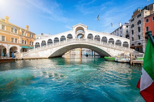 Famous buildings, gondolas and monuments by the Rialto Bridge of Venice on the Grand Canal, Italy.