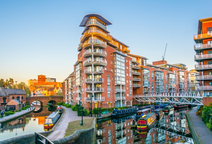 Photo of sunset view of brick buildings alongside a water channel in the central Birmingham, England.