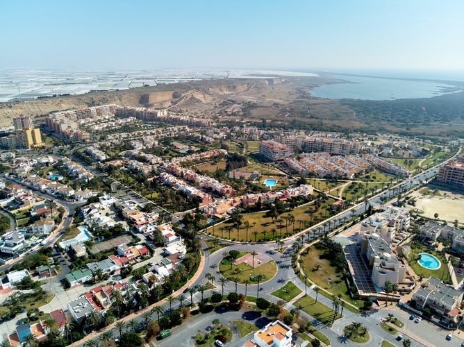 Aerial wide drone point of view photography Almerimar townscape with residential houses streets and roads, lot of greenhouses Victoria lake. El Ejido municipality in Almeria province. Andalucia, Spain