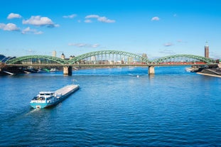 Cologne Aerial view with trains move on a bridge over the Rhine River on which cargo barges and passenger ships ply. Majestic Cologne Cathedral in the background.