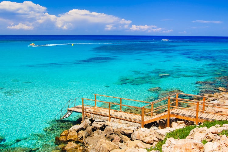 Photo of wooden platform with steps to azure sea water near Protaras, Cyprus island.