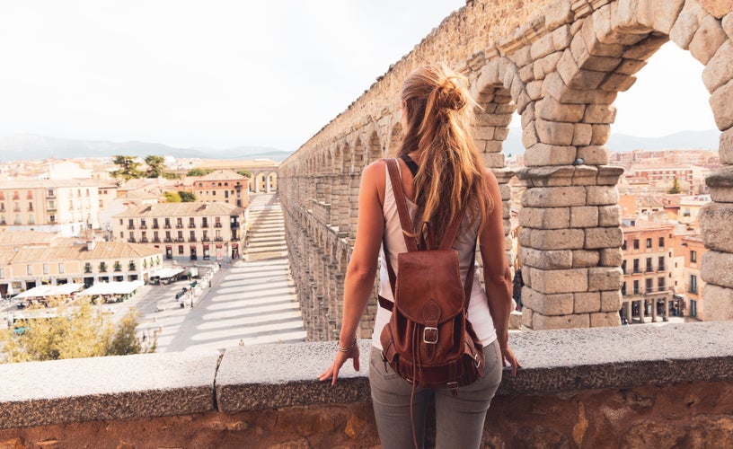 photo of view of Tourism at Segovia, rear view of woman tourist enjoying view of Roman aqueduct on plaza del Azoguejo in Spain