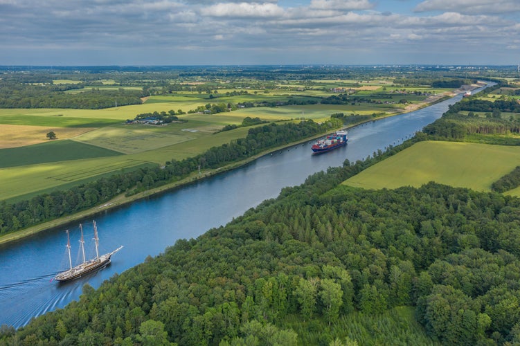 Photo of Aerial view of Kiel Canal with container ship and traditional sailing vessel.Container cargo ship and tall ship on the Kiel Canal between Baltic sea and North Sea Schleswig Holstein, Germany.