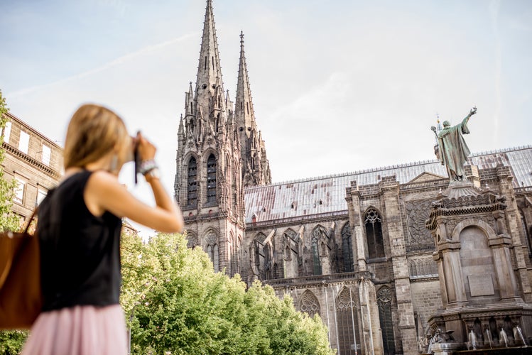 Photo of woman enjoying morning view on the famous cathedral in Clermont-Ferrand city in France.