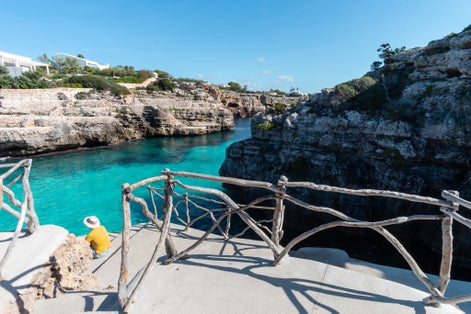 photo of a man with a perspective view at turquoise waters of Cala en Brut, Menorca beach, Balearic Islands, Spain.