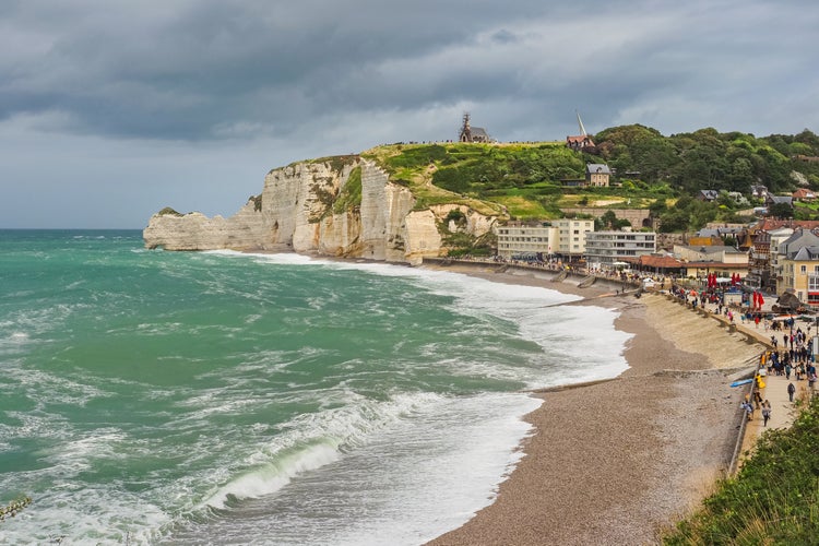 Panoramic view to white Étretat rock Falaise d'Amont. Steep vertical chalk cliff with a natural arch, and beach below, washed by the stormy Atlantic Ocean. Alabaster Coast, Normandy, France.