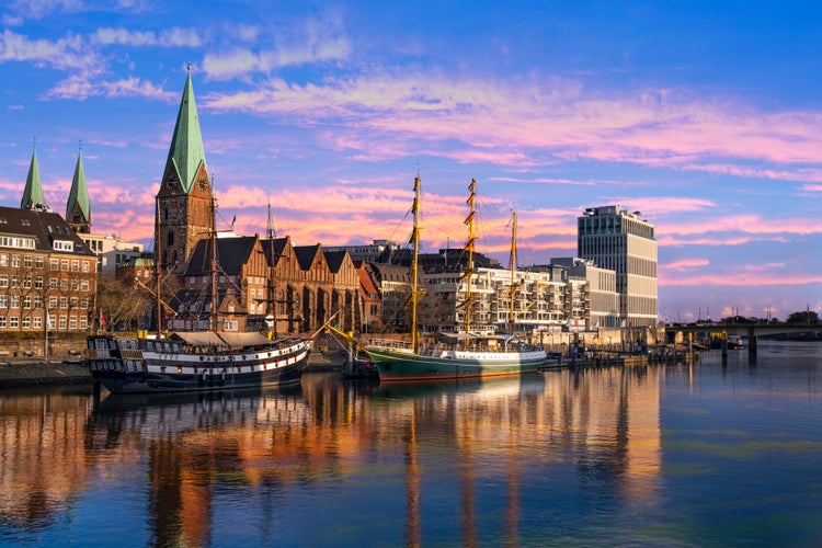 Photo of In der DÃ¤mmerung liegen Dreimaster vor der Promenade an der Weser in Bremen.