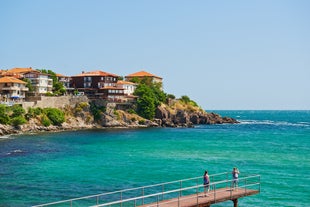 Photo of Saint Anastasia Island in Burgas bay, Black Sea, Bulgaria. Lighthouse tower and old wooden buildings on rocky coast.