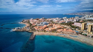 photo of aerial shot of Costa Adeje area, South Tenerife, Spain. Captured at golden hour, warm and vivid sunset colors. Luxury hotels, villas and restaurants behind the beach.