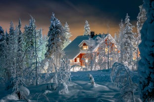 Photo of stunning sunset view over wooden huts and snow covered trees in Kuusamo, Finnish Lapland.