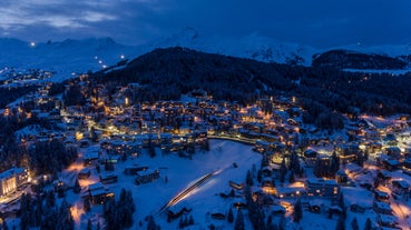 photo of beautiful snow capped mountains with Arosa village in France. Back country skier in the foreground leave their tracks in the deep snow.