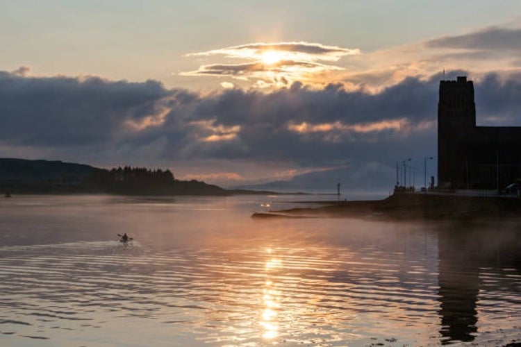 A person kayaking at sunset near the port of Oban on the west coast of Scotland.jpg