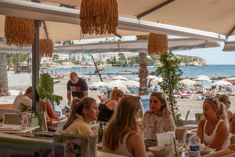 Girlfriends enjoy a drink and a snack in a cozy restaurant near the beach of Ses Figueretes in Ibiza.jpg