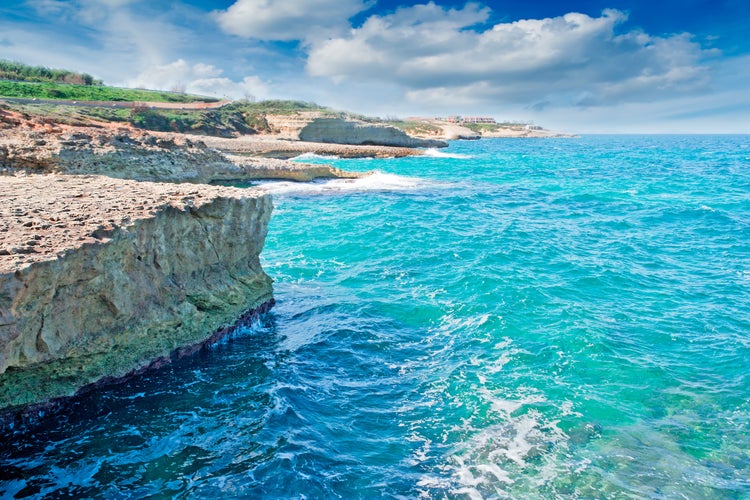 Photo of Porto Torres rocky shore with beautiful blue water on a sunny day. Sardinia, Italy.