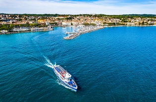 Photo of Old harbour Porto Vecchio with motor boats on turquoise water, green trees and traditional buildings in historical centre of Desenzano del Garda town, Northern Italy.