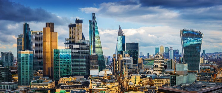 Photo of London, England - Panoramic skyline view of Bank and Canary Wharf, central London's leading financial districts with famous skyscrapers at golden hour sunset with blue sky and clouds.