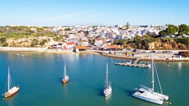 Photo of beautiful aerial view of the sandy beach surrounded by typical white houses in a sunny spring day, Carvoeiro, Lagoa, Algarve, Portugal.