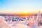 Photo of stunning sunset view over wooden huts and snow covered trees in Kuusamo, Finnish Lapland.