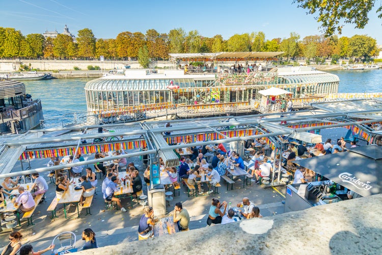 People sitting at the terrace of Peniche Rosa Bonheur on the quays of the Seine river on a sunny day.jpg