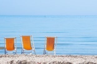 Photo of beach chairs, on a sandy, shoreline, in Giulianova, Italy.